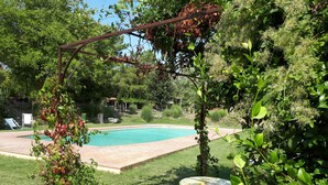 Un jardin avec une piscine, une pergola et une table entourée de chaises.