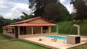 Ein Haus mit Swimmingpool, überdachter Terrasse und Rasen.