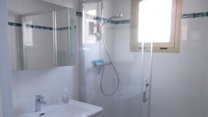 Une salle de bain avec un lavabo blanc, un miroir et un espace douche.