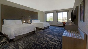 Une chambre d’hôtel avec deux lits, un bureau, une chaise et un téléviseur.