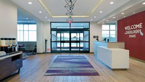 Un espace d’accueil au design moderne, comprenant un comptoir d’accueil, une grande fenêtre et une enseigne indiquant : « Bienvenue en Californie ».