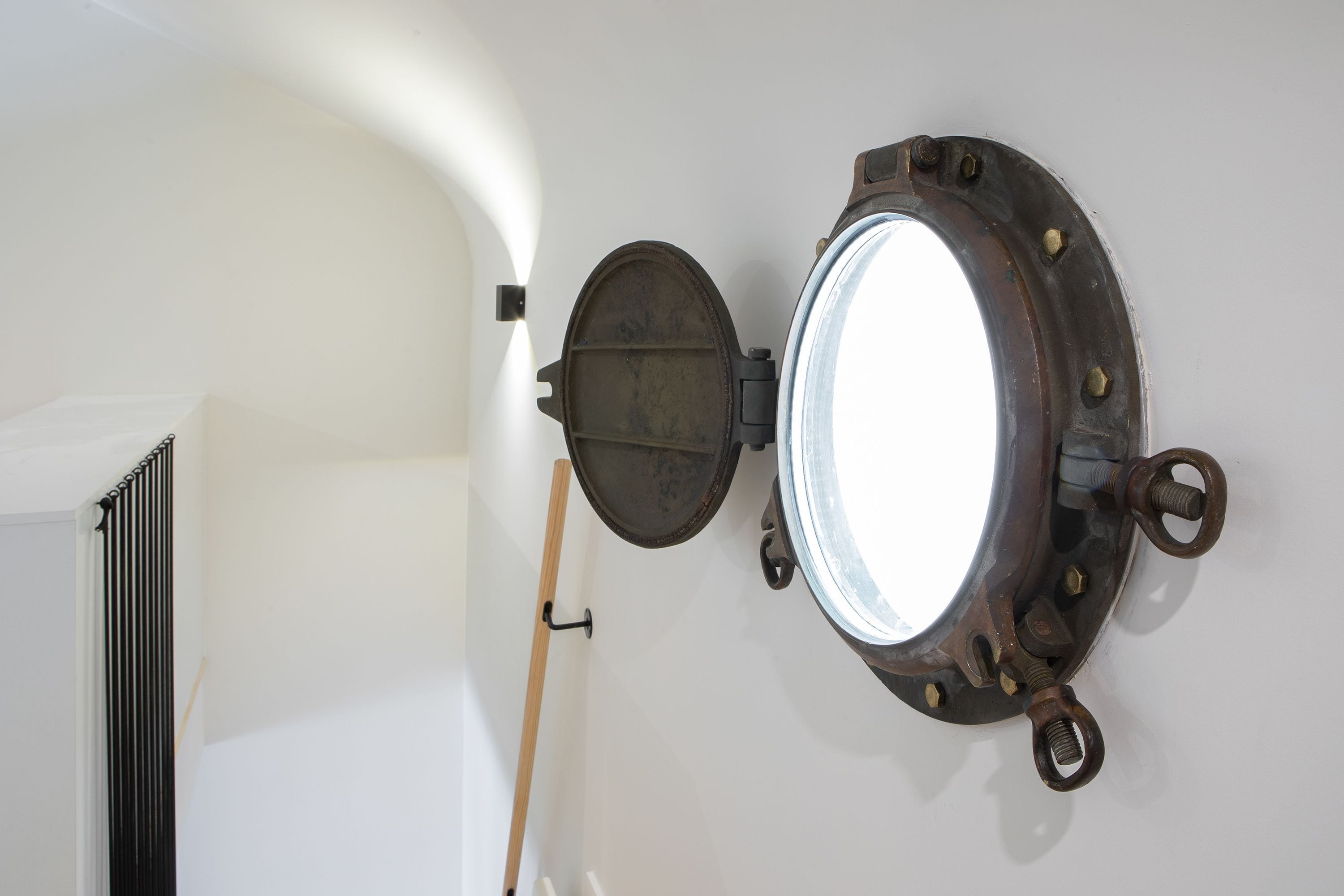 A circular mirror with a metal frame mounted on a white wall.