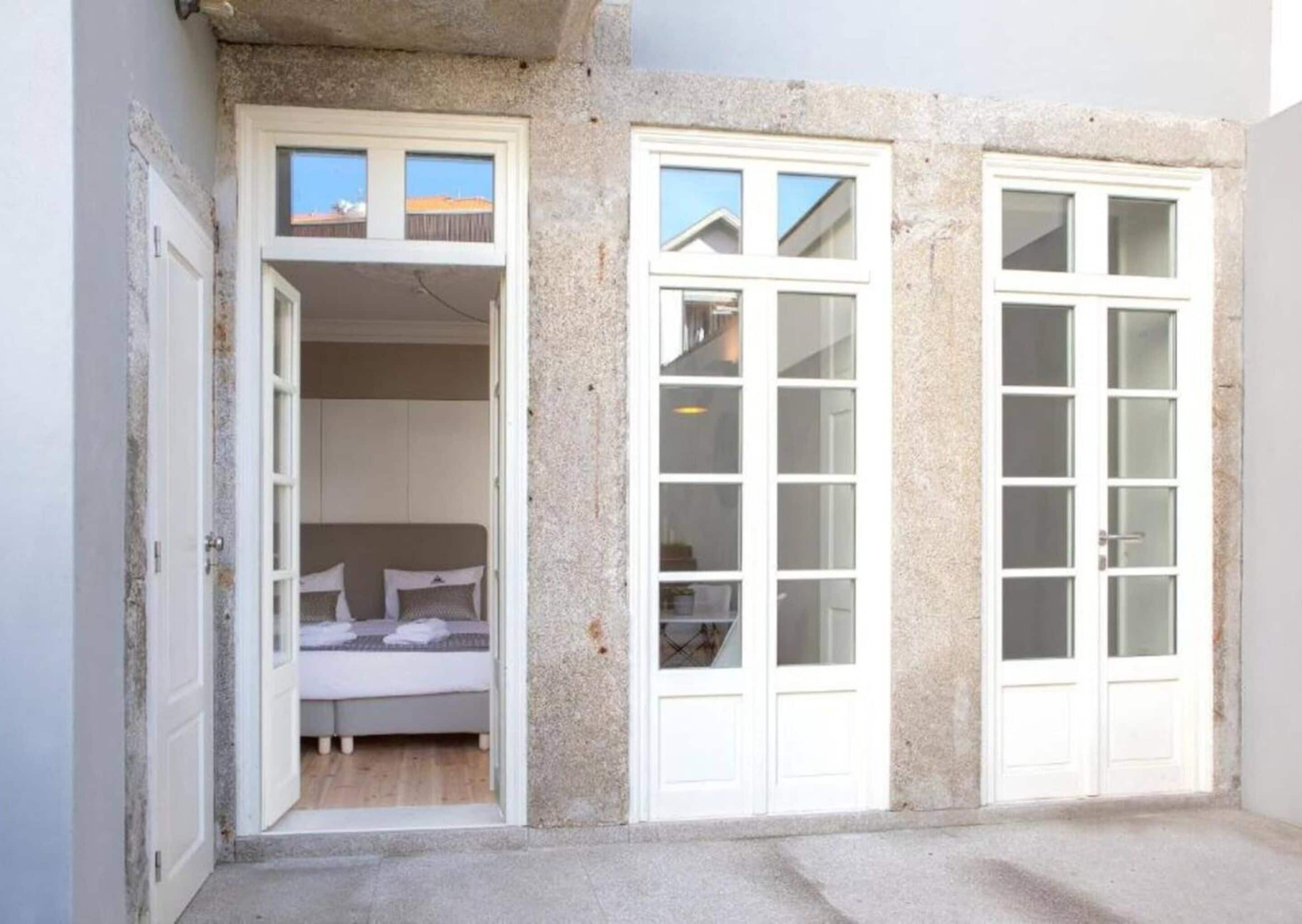 A small, enclosed room with a bed, two windows, and a door.