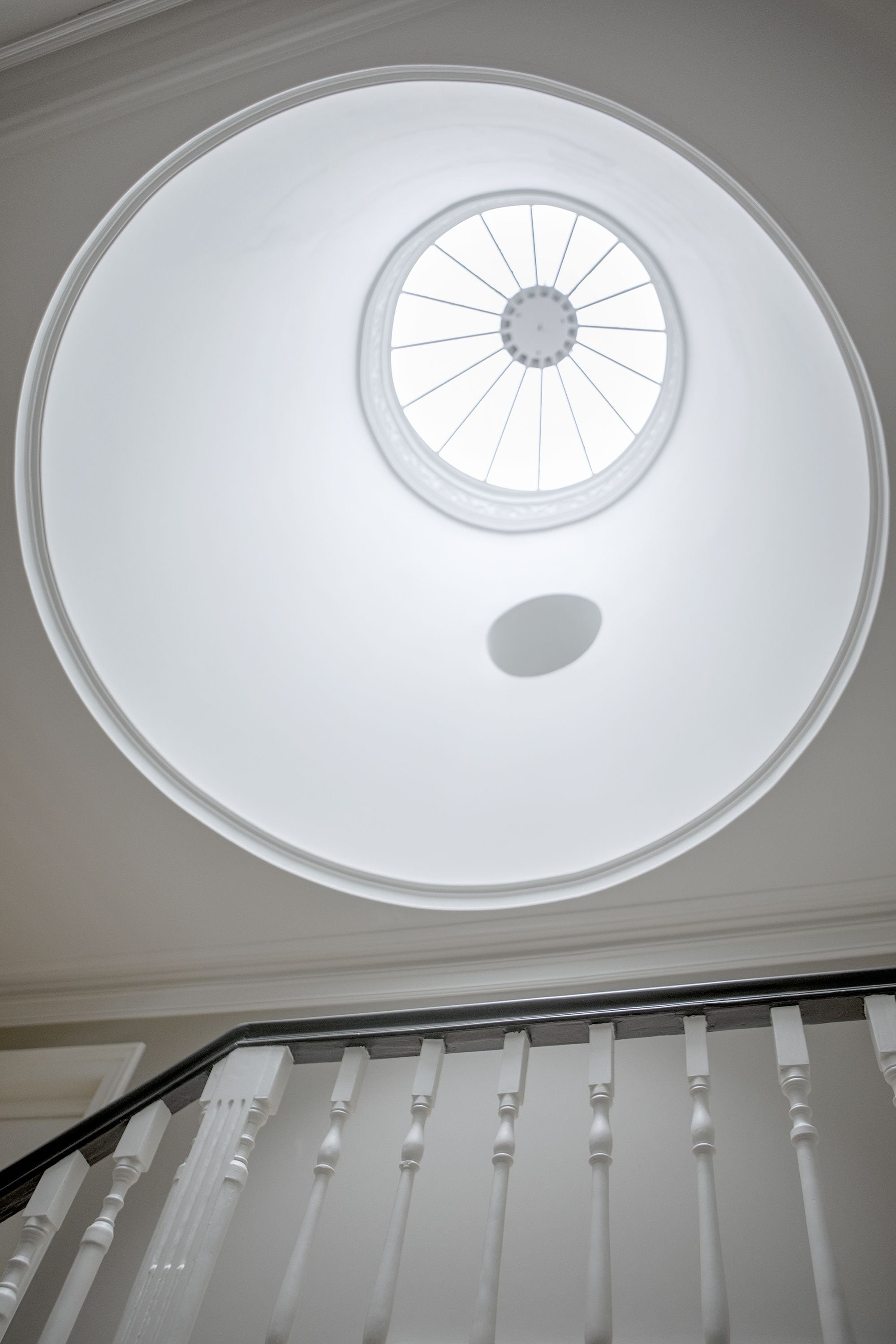 Une lucarne circulaire dotée d’une fenêtre centrale et d’une plus petite ouverture circulaire en dessous.