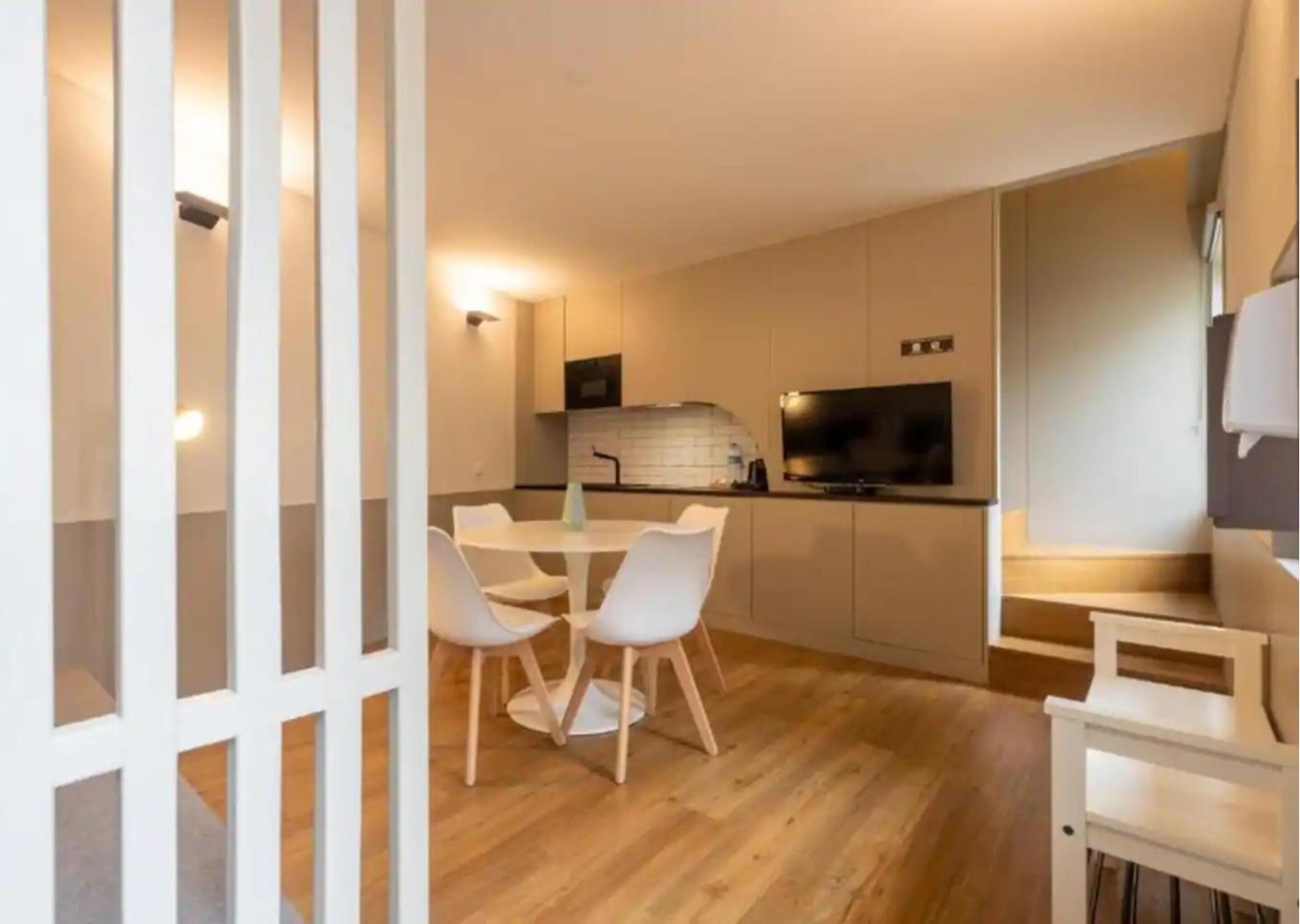 Een moderne keuken met witte kasten, een centraal eiland en een eetgedeelte met witte stoelen.