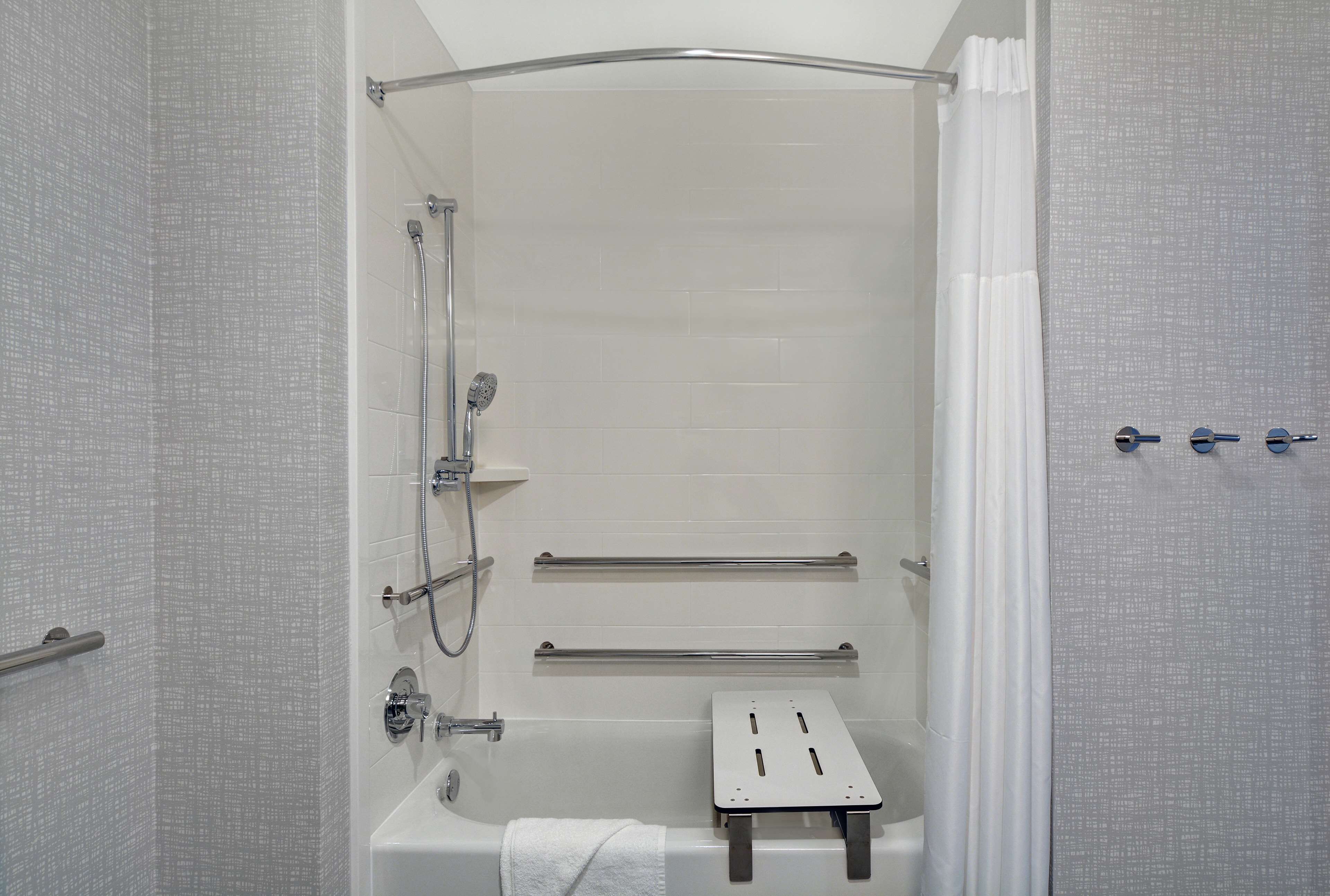 A shower with a glass door, a towel rack, and a small step stool.