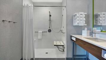 Un baño moderno con ducha a nivel del suelo, tocador con espejo y perchero.