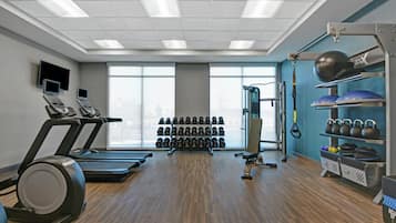 Academia com esteiras, racks de peso, kettlebells e equipamentos de ginástica.