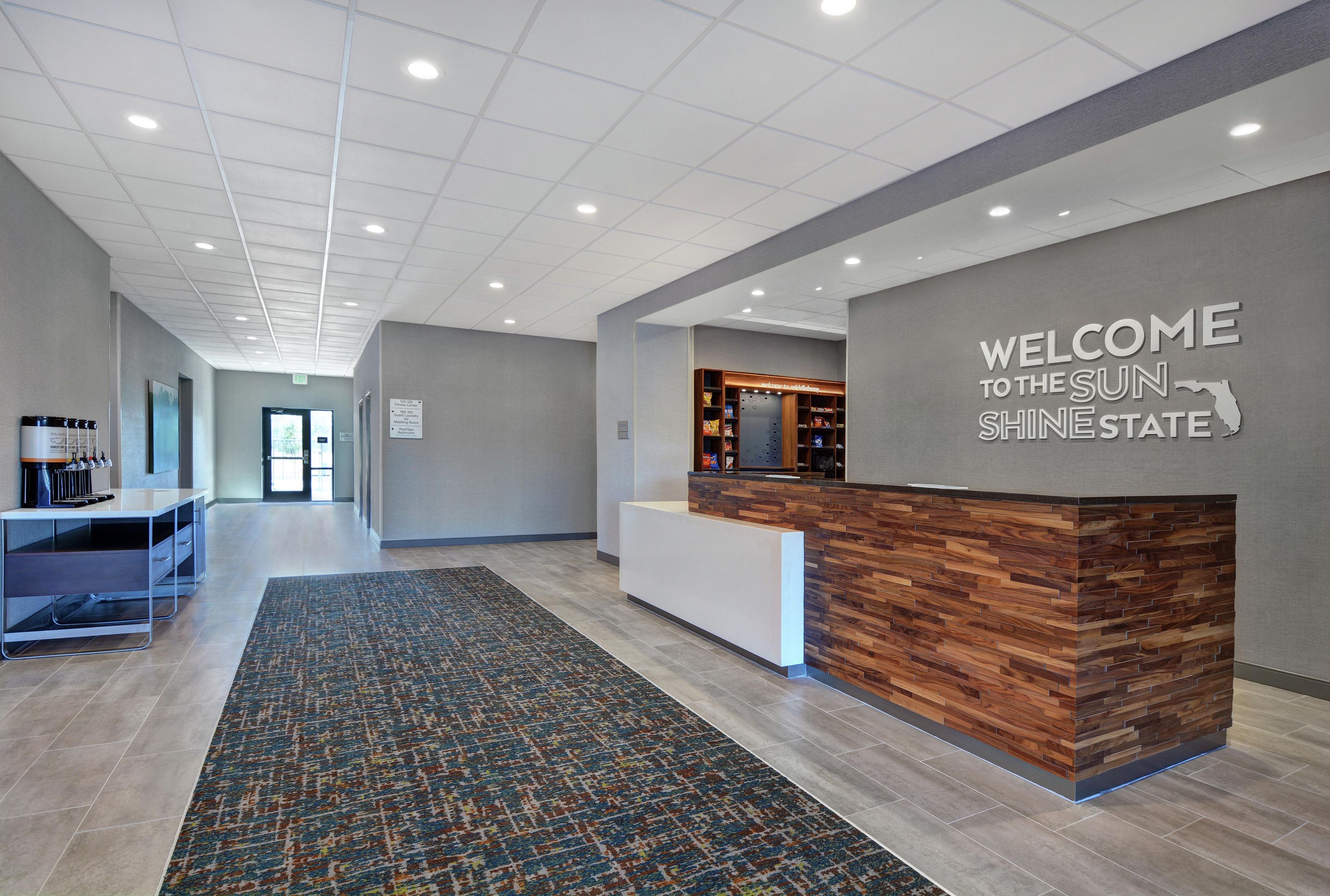 A reception area with a wooden reception desk, a welcome sign, and a patterned carpet.