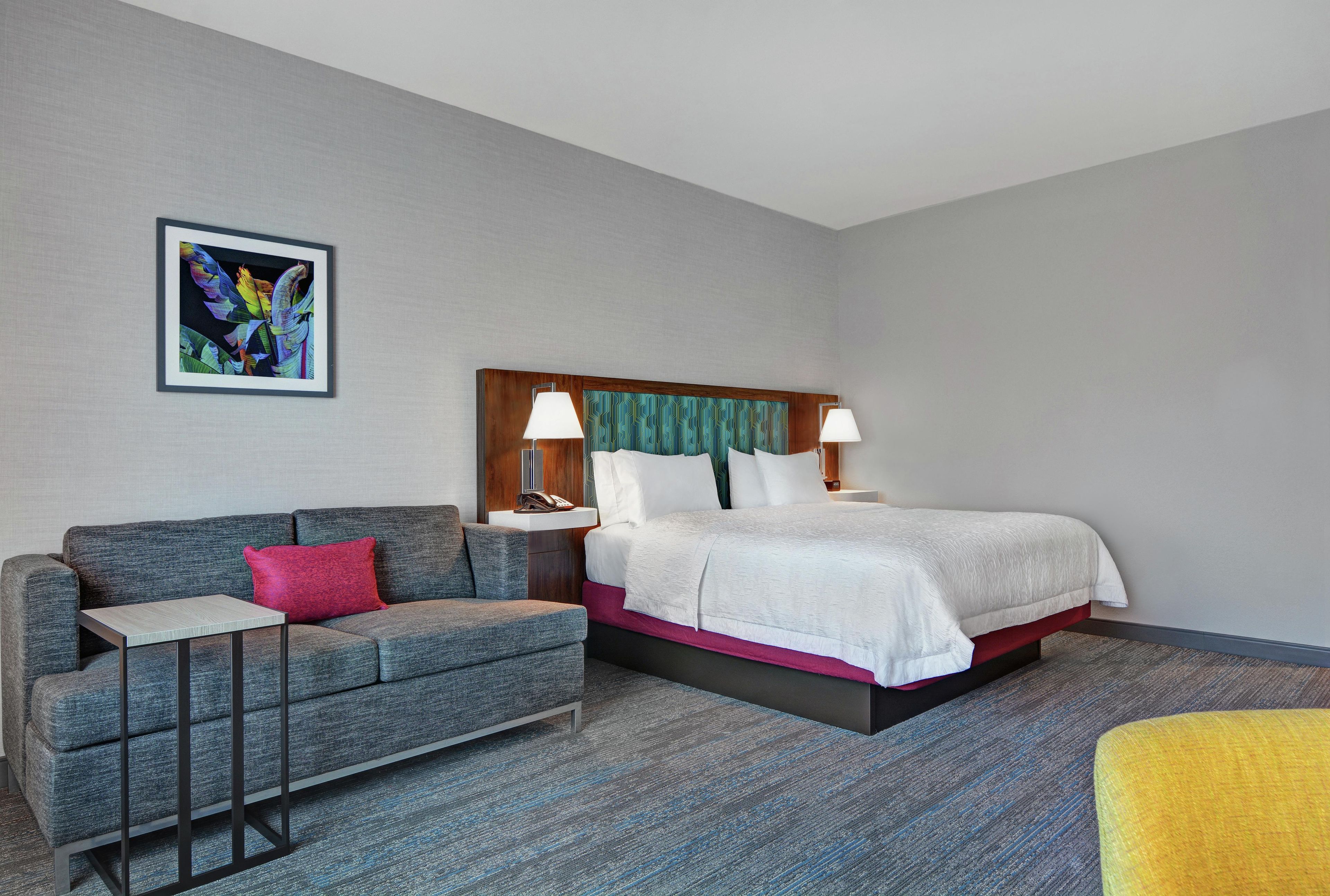 Una habitación de hotel con cama, sofá, una mesita y una silla.
