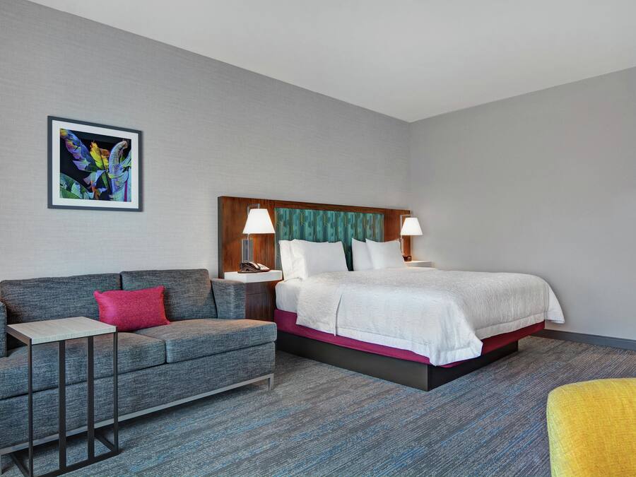Una habitación de hotel con cama, sofá, una mesita y una silla.
