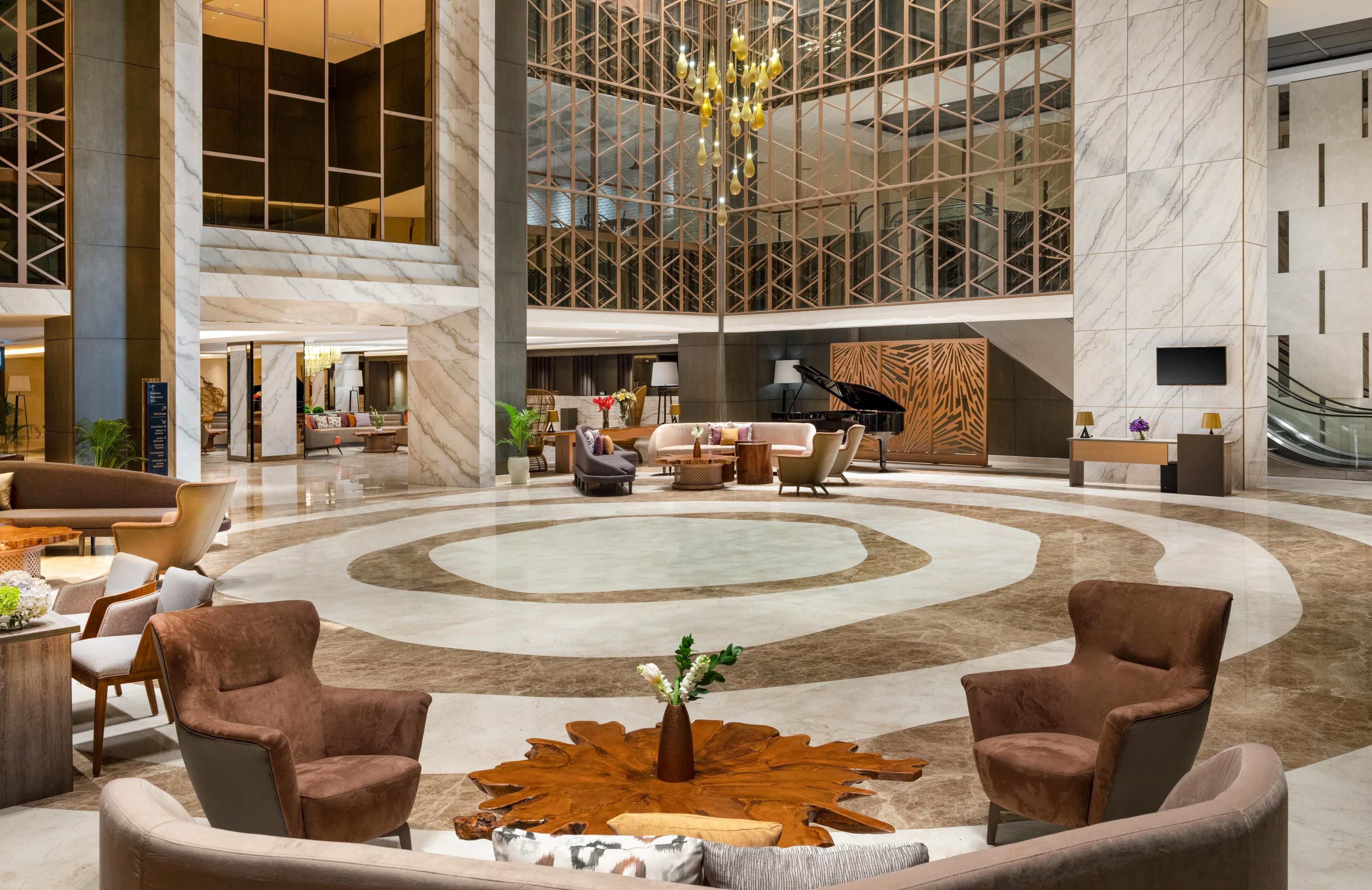 A spacious lobby with a grand piano, comfortable seating, and a large chandelier.