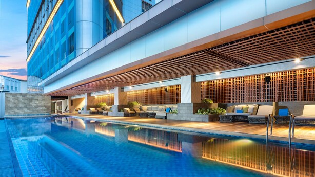 A modern hotel with a swimming pool, outdoor seating, and a contemporary design. - Doubletree By Hilton Surabaya (Surabaya)