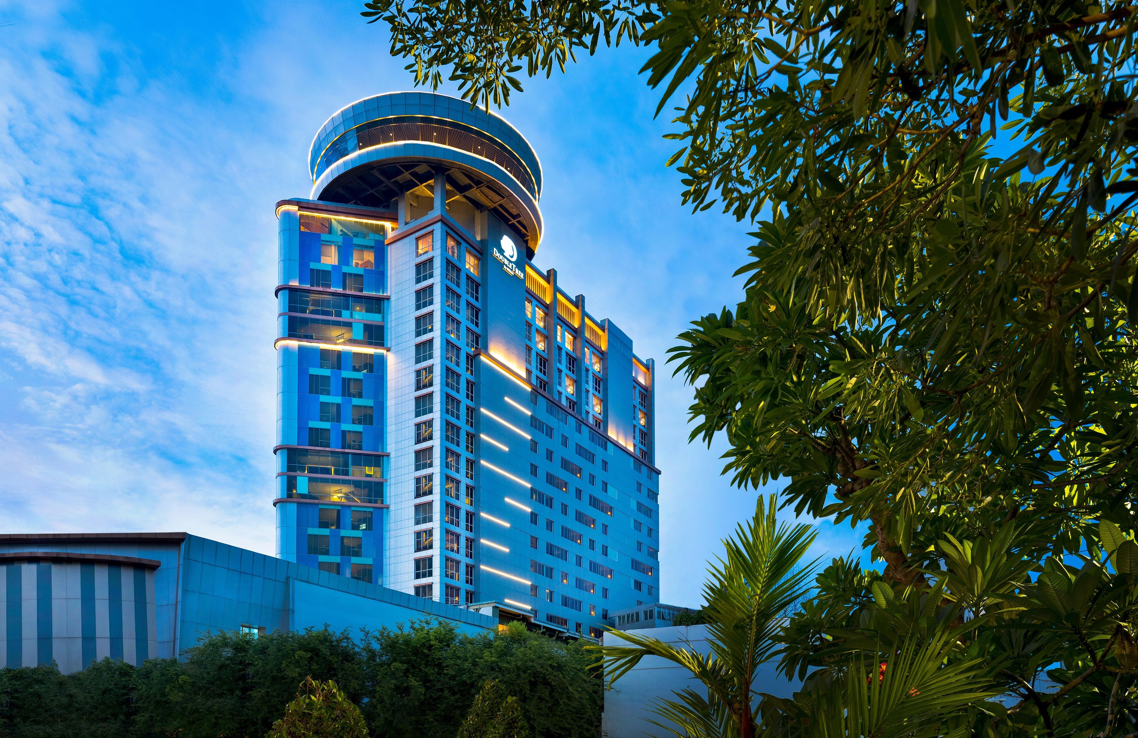 A modern hotel building with a curved top, multiple floors, and a prominent 'DoubleTree' sign.
