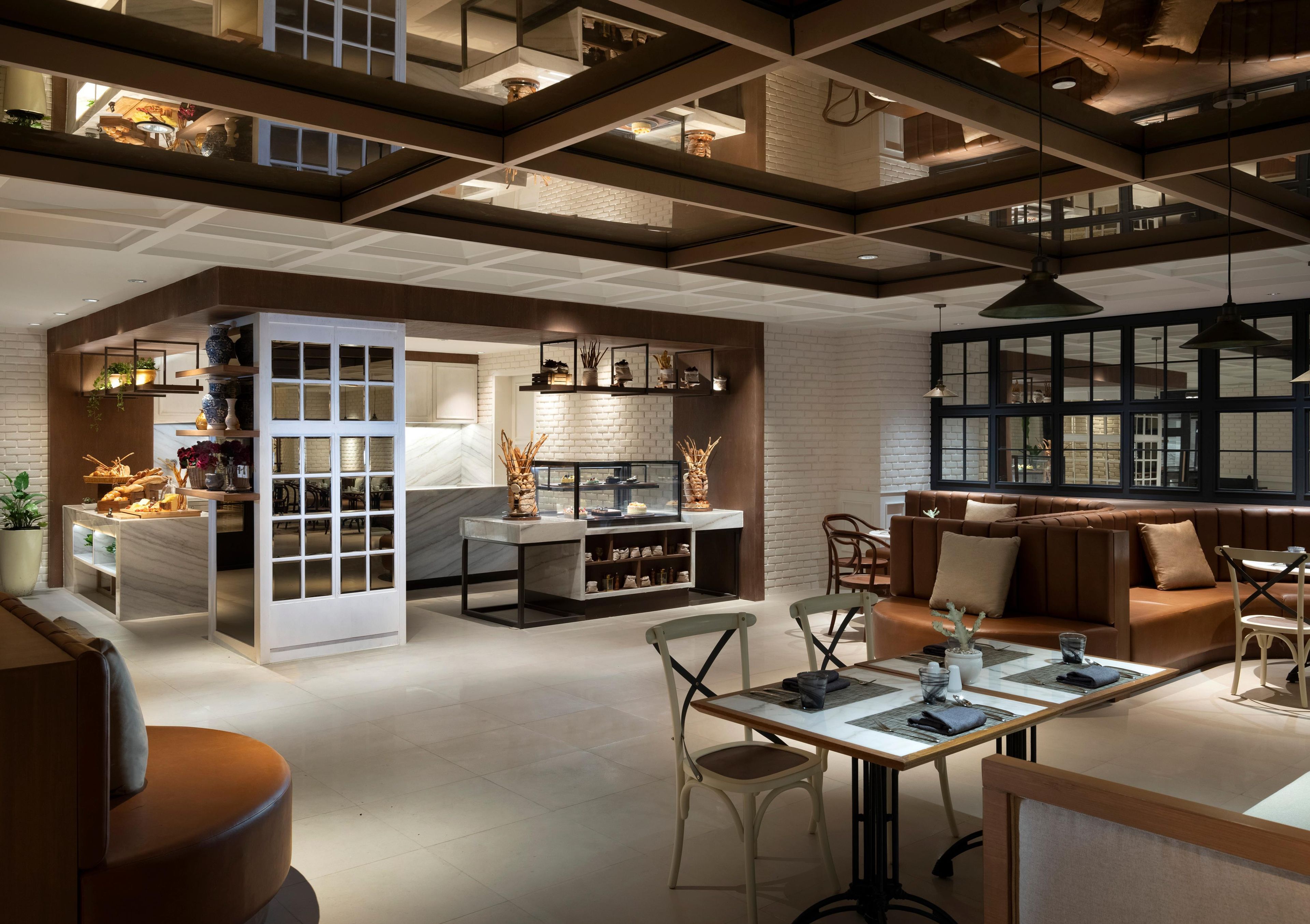 A modern interior with a dining area, seating, and a kitchen visible through a glass partition.