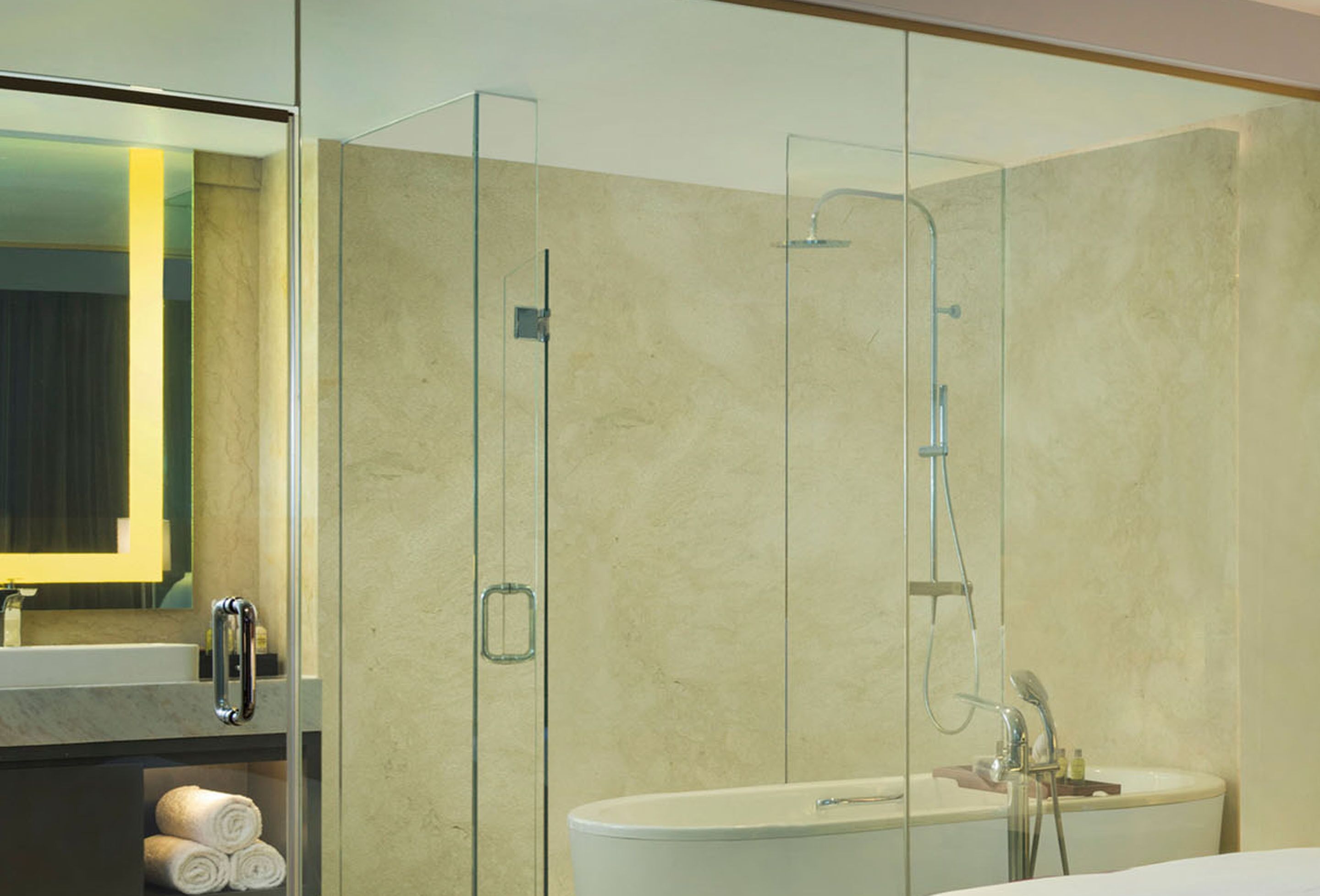 Een moderne badkamer met een douchecabine van glas, een witte badkuip en een wastafel met spiegel en handdoekhouder.