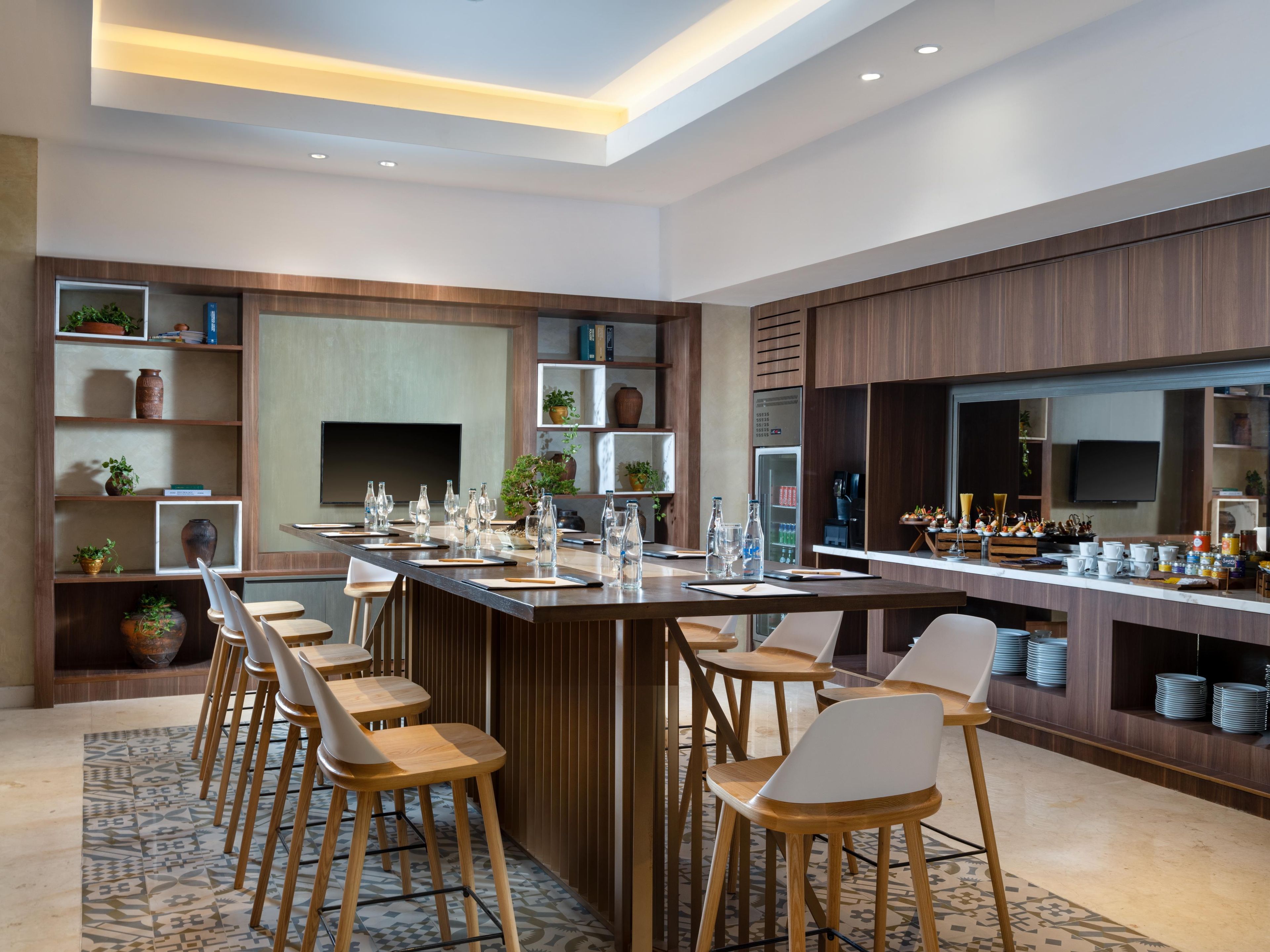 Une cuisine moderne dotée d’un îlot central, de tabourets de bar et d’étagères intégrées où sont exposés des objets décoratifs.