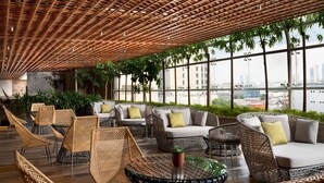 A modern lounge with wicker furniture, large windows, and a city view. - Doubletree By Hilton Surabaya (Surabaya)