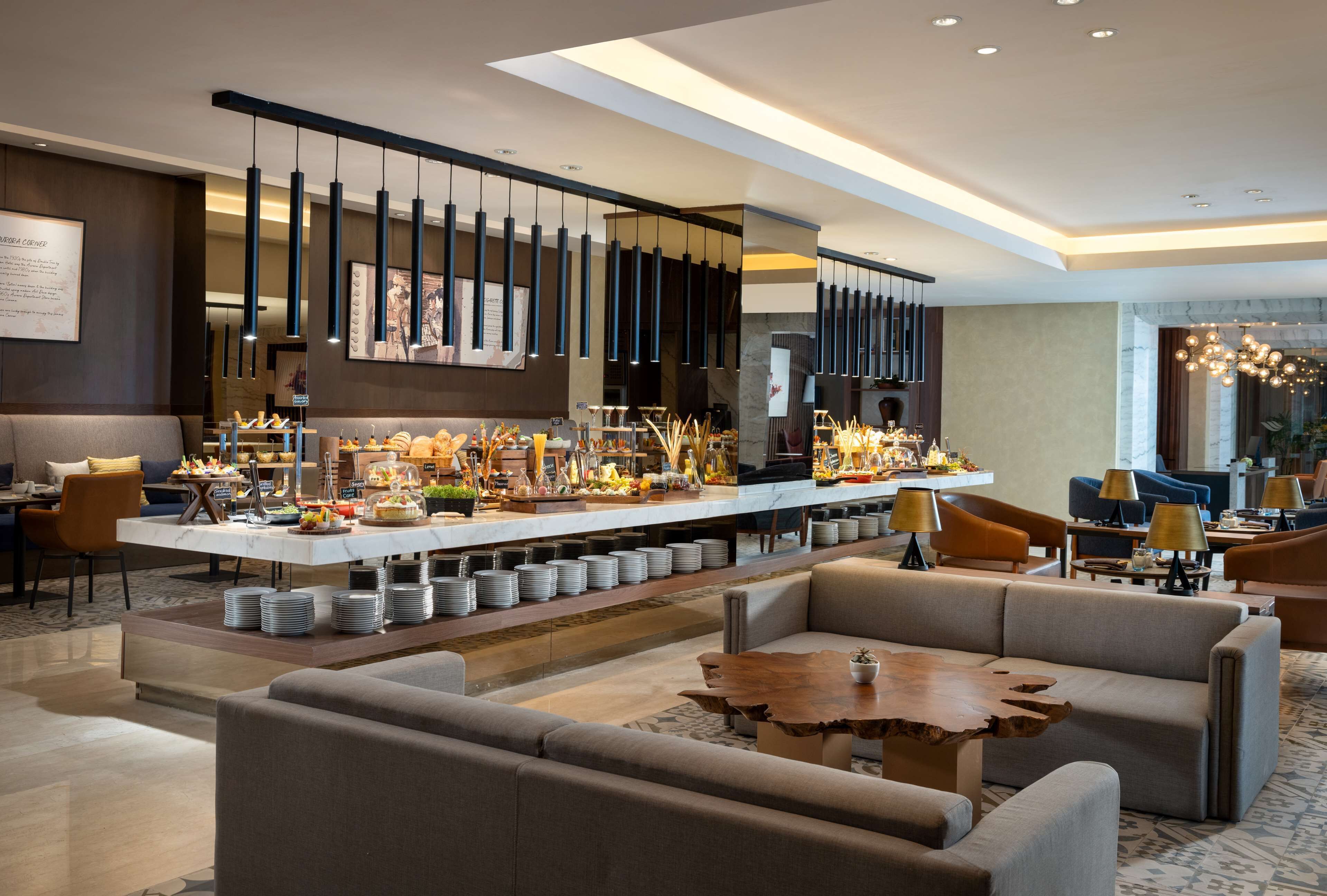 A modern hotel lobby with a central bar area, seating arrangements, and a chandelier.