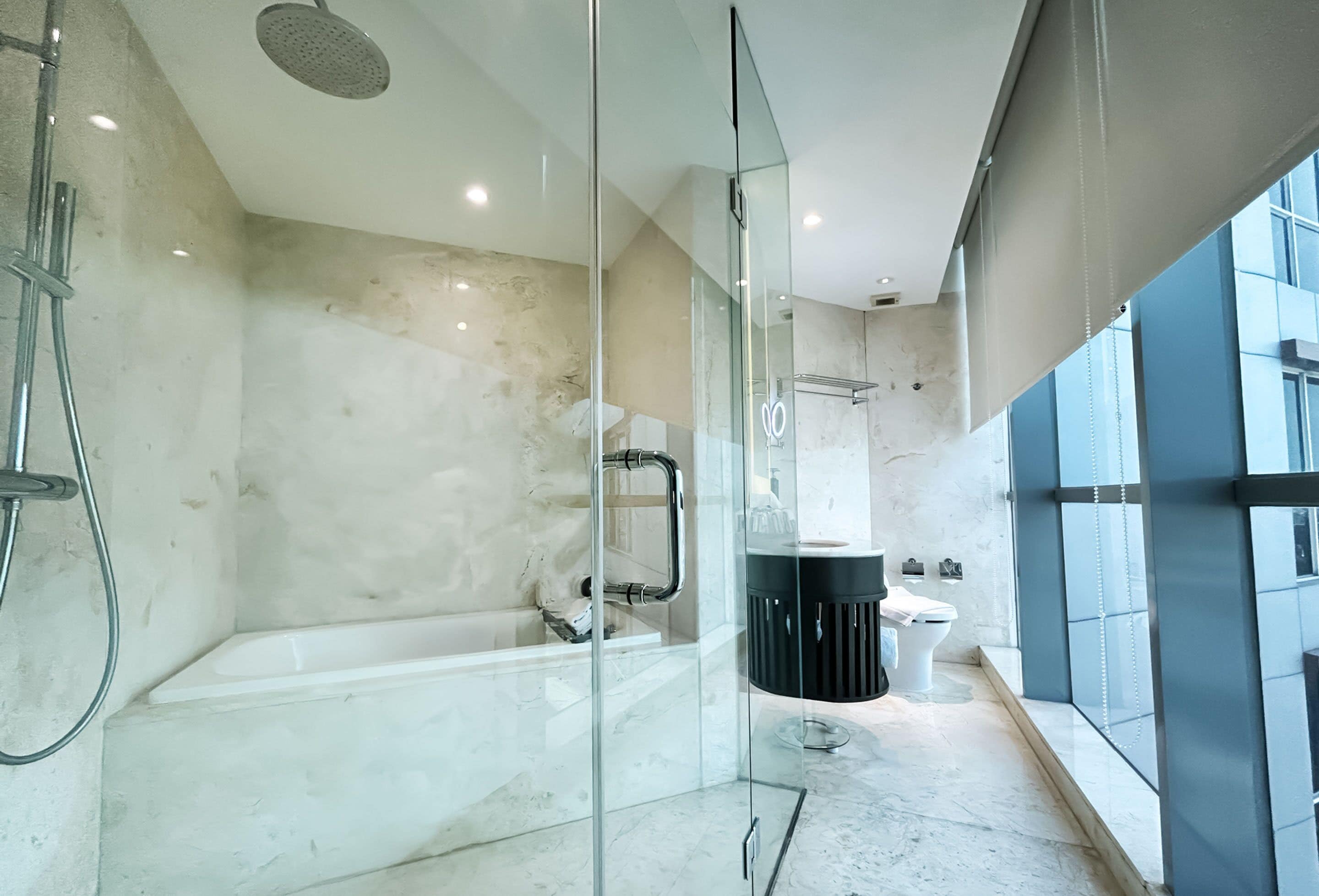 Un baño moderno con ducha de vidrio, una bañera blanca y un lavabo negro.