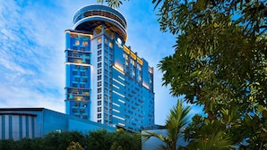 A modern hotel with a cylindrical top, multiple floors, and a well-lit facade. - Doubletree By Hilton Surabaya (Surabaya)