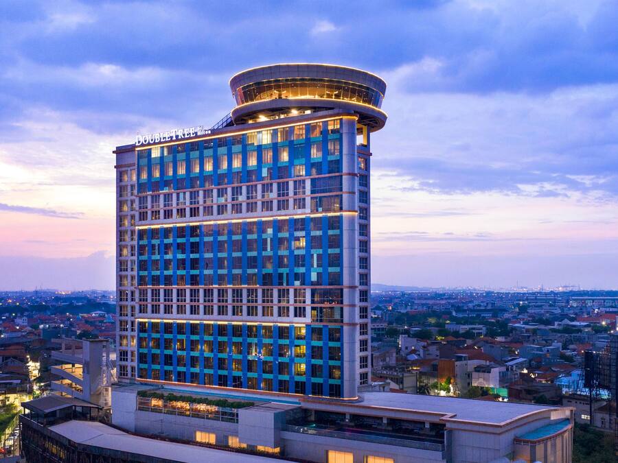 A high-rise hotel with a modern design, featuring a prominent cylindrical top section and a grid of windows.