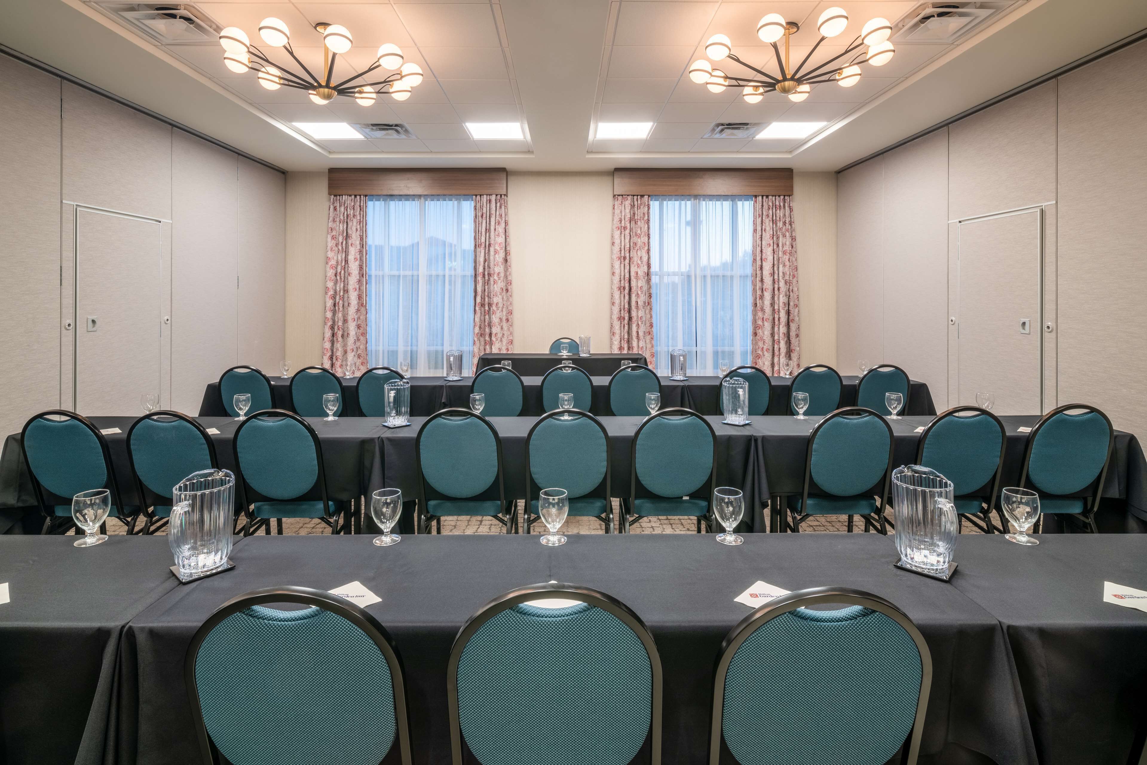 A conference room with a long table, multiple chairs, and glassware.