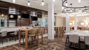 Un restaurante moderno con barra, piso de madera y luminarias contemporáneas.
