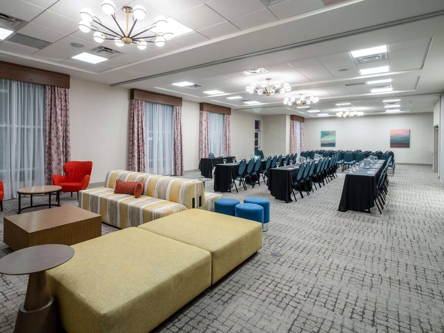 Una habitación de hotel espaciosa con una amplia zona de estar, una mesa de conferencias y suelo alfombrado.