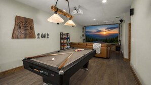 Una mesa de billar con techo de madera y un mural al fondo que representa un atardecer.