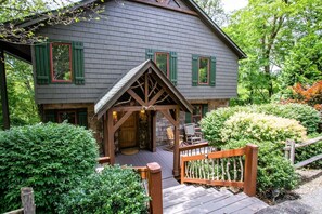 A wooden house with a porch, a stone entrance, and a wooden fence.