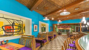 Un restaurant avec des banquettes et des tables en bois, un sol à carreaux et un mur bleu.