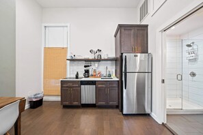 Eine kompakte Küche mit dunklen Holzausziehtüren, einem Edelstahl-Kühlschrank und einem Geschirrspüler.