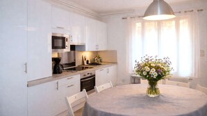 A modern kitchen with white cabinets, a microwave, a coffee maker, and a dining table with chairs. - La Ferme de Balizy is a property in Longjumeau, near Paris, Versailles, and Massy. (Longjumeau)