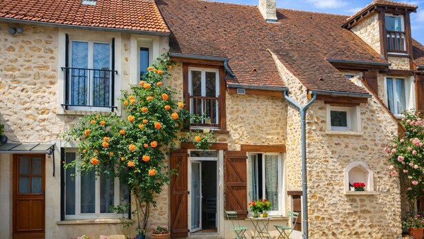 A stone building with a tiled roof, a wooden door, and a small balcony. - La Ferme de Balizy is a property in Longjumeau, near Paris, Versailles, and Massy. (Longjumeau)