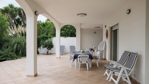 A covered patio with a table and chairs, surrounded by greenery and a tiled floor. - Magnificent sea view villa with large garden, a few steps from the sea (Gallipoli)