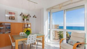 A modern kitchen with a dining table, chairs, and a view of the sea through large windows. - Apartment Gala I by Interhome (Miami Platja)