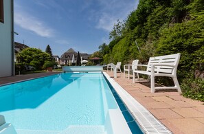 A swimming pool with white chairs and a clear blue sky. - Hotel Winzerverein (Zeltingen-Rachtig)