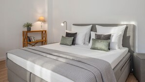 A neatly made bed with a grey headboard, a bedside table with a lamp, and a small plant. - Cozy vacation apartment in Heringsdorf close to the beach (Seebad Heringsdorf)