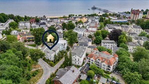 An aerial view of a coastal town with a prominent pier, dense residential buildings, and a marked location. - Cozy vacation apartment in Heringsdorf close to the beach (Seebad Heringsdorf)