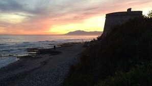 A coastal landscape with a rocky beach, a stone structure, and a distant mountain range. - Andalusian villa, pool 4x8m, 2 double beds, beach 400M, close to restaurants (Las Chapas)