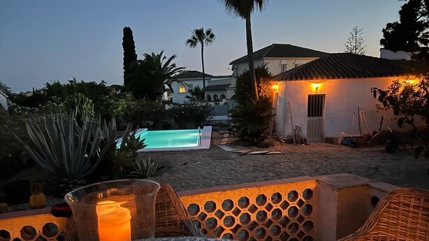 A patio with wicker furniture, a glass table with a candle, a pool, and a house with a tiled roof in the background. - Andalusian villa, pool 4x8m, 2 double beds, beach 400M, close to restaurants (Las Chapas)