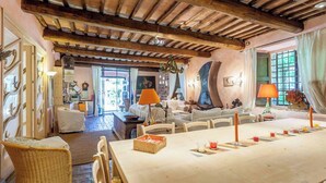 Un grand espace dédié à la salle à manger, avec une longue table, de nombreuses chaises et deux lampes.