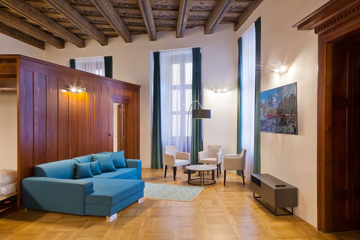 A modern living room with a blue sofa, a round coffee table, and a painting of a cityscape.
