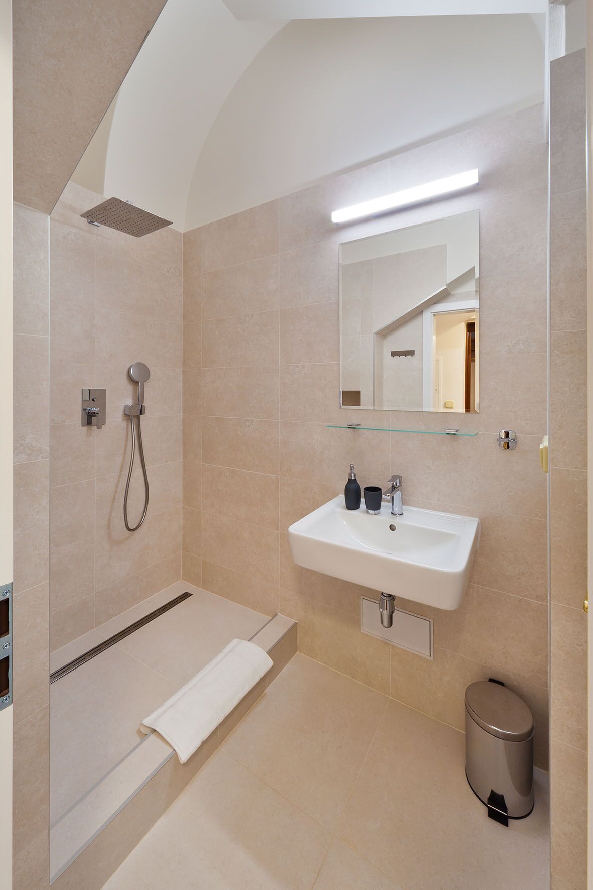Un baño moderno con ducha a ras de suelo, un lavabo con espejo y un inodoro.