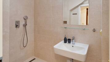 Un baño moderno con ducha a ras de suelo, un lavabo con espejo y un inodoro.