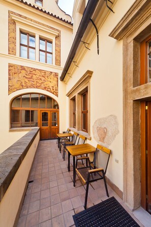 A courtyard with outdoor seating, a stone wall, and a mural. - Residence u Vejvodů (Prague)