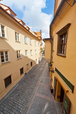 A narrow cobblestone street flanked by buildings with uniform, cream-colored facades and red-tiled roofs. - Residence u Vejvodů (Prague)