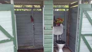 A small, rustic wooden structure with a single toilet and a flower vase. - Traditional Bure by the beach in the authentic Yasawa Village (Yasawa islands)