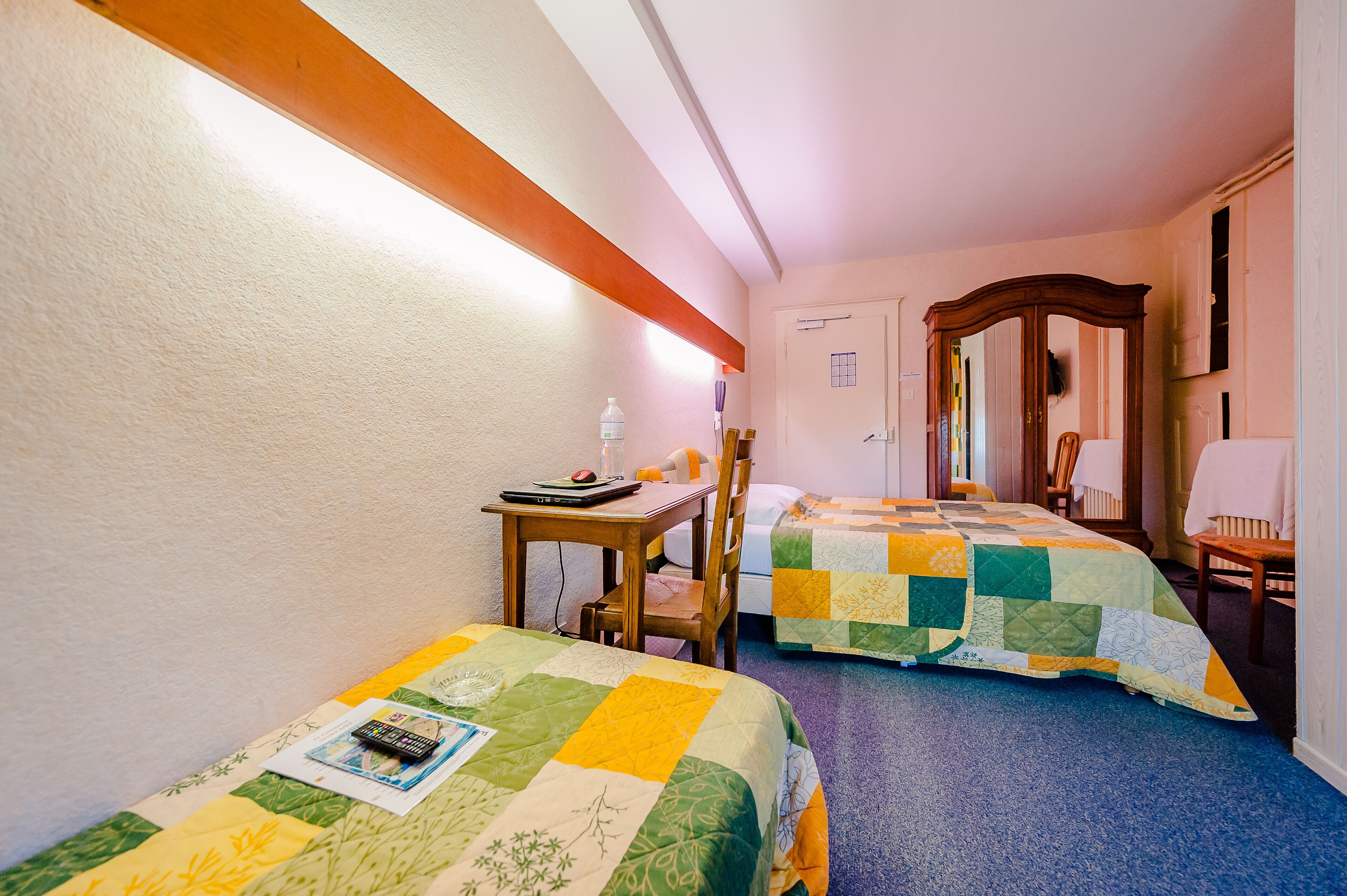 Ein Hotelzimmer mit zwei Betten, einem Schreibtisch, einem Stuhl und einem Tisch.